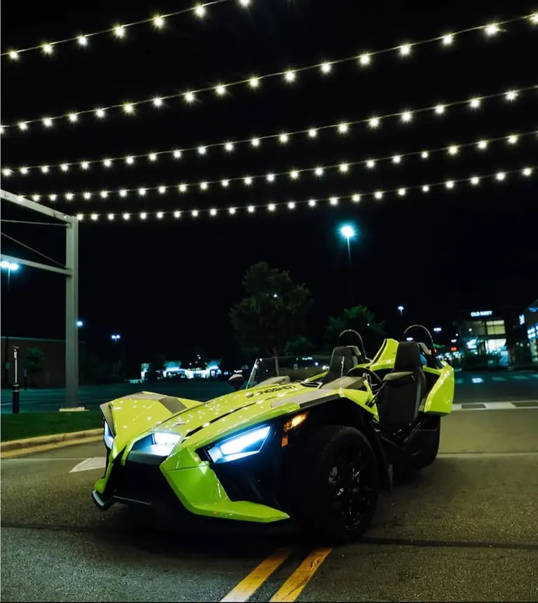 Lime Polaris Slingshot under string lights at night